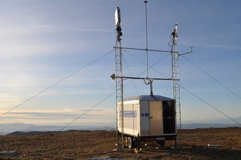 Experimental site of the ground campaign. The polarimetric GNSS RO antenna and the L-band radiometer are located on two separate towers. The rest of equipment is locked in the shelter. The site has clear views over the horizon, above an area in which intense precipitation happens a few times every year.